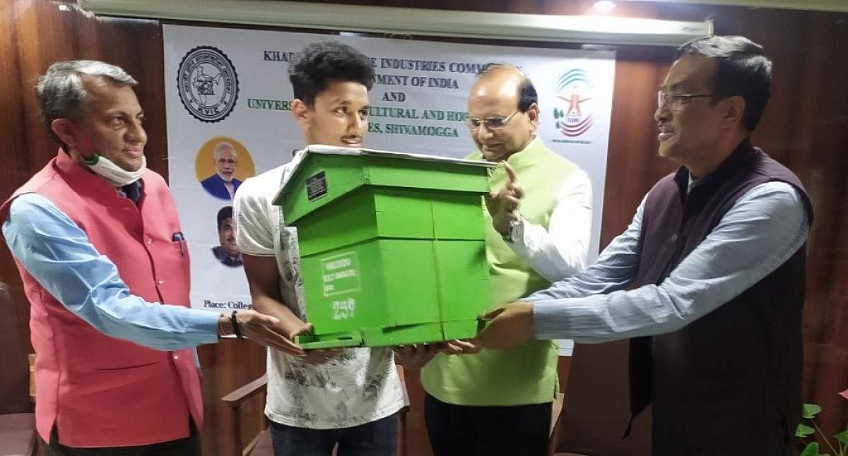 KVIC president Vinaykumar Saxena distributes honey bee colonies to a traineeduring a programme held at the College of Forestry in Ponnampet. Credit: DH Photo