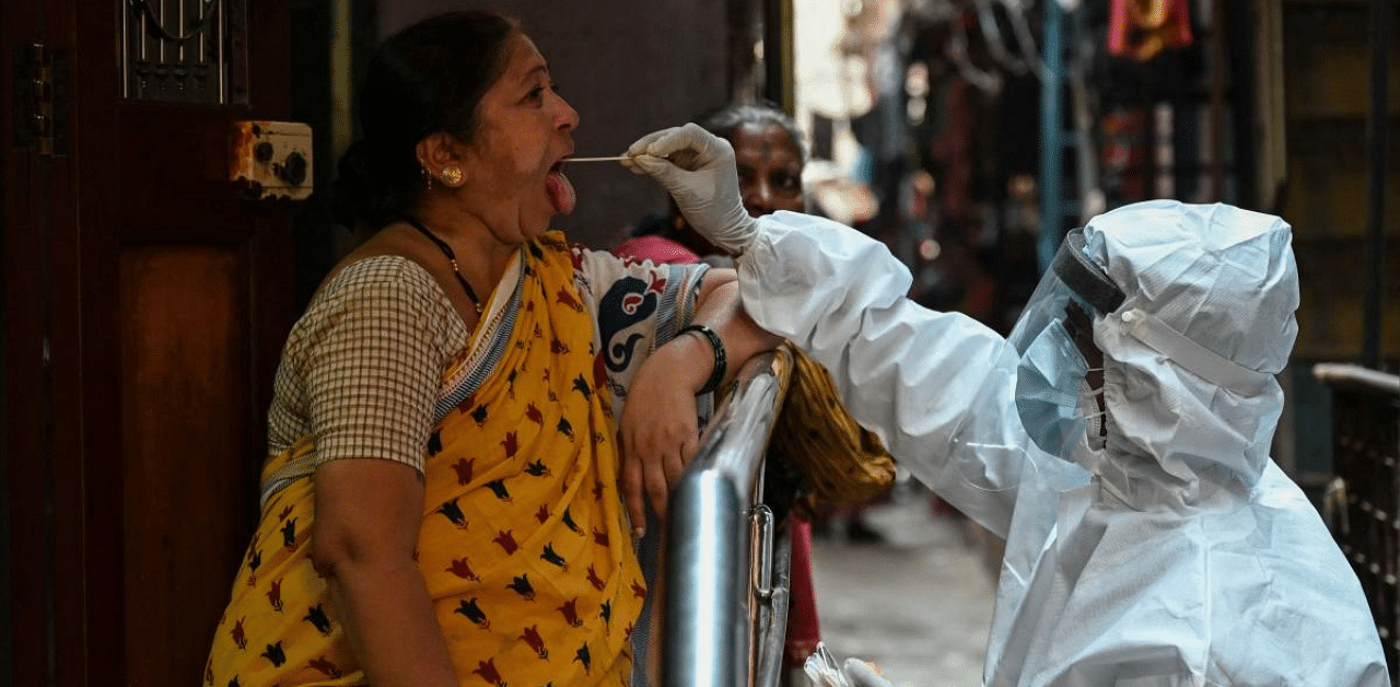 A health worker wearing protective gear takes a swab sample in Maharashtra. Credit: AFP photo. 