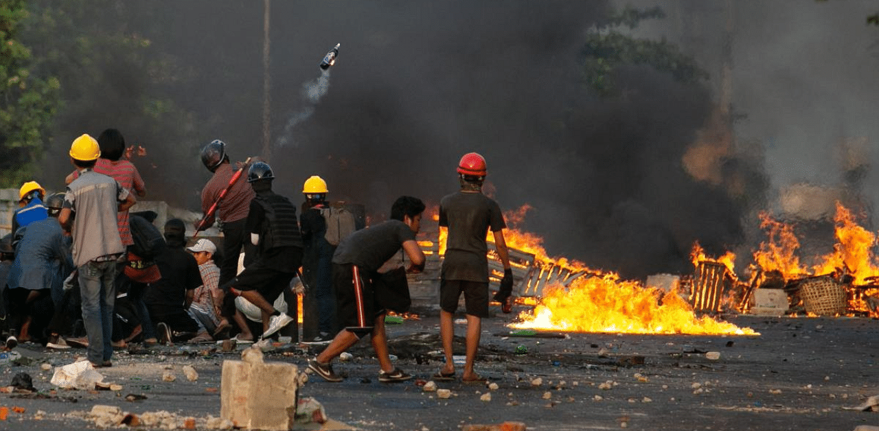 A protester throws a petrol bomb as other take cover behind homemade shields as they confront the police during a crackdown on demonstrations against the military coup in Yangon. Credit: AFP photo. 