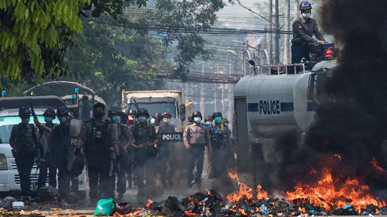 Security forces gather behind a burning barricade during a crackdown on protests against the military coup in Yangon on March 17, 2021. Credit: AFP Photo