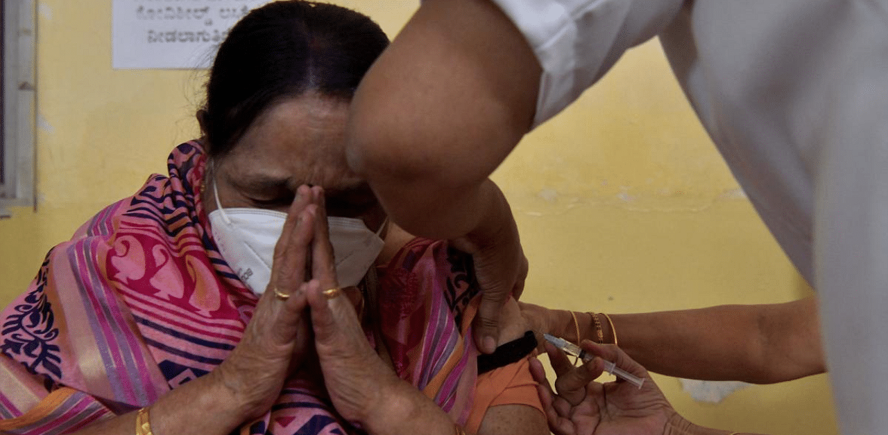 A health worker (R) inoculates a senior citizen with a coronavirus vaccine at a government hospital in Bengaluru. Credit: AFP photo. 