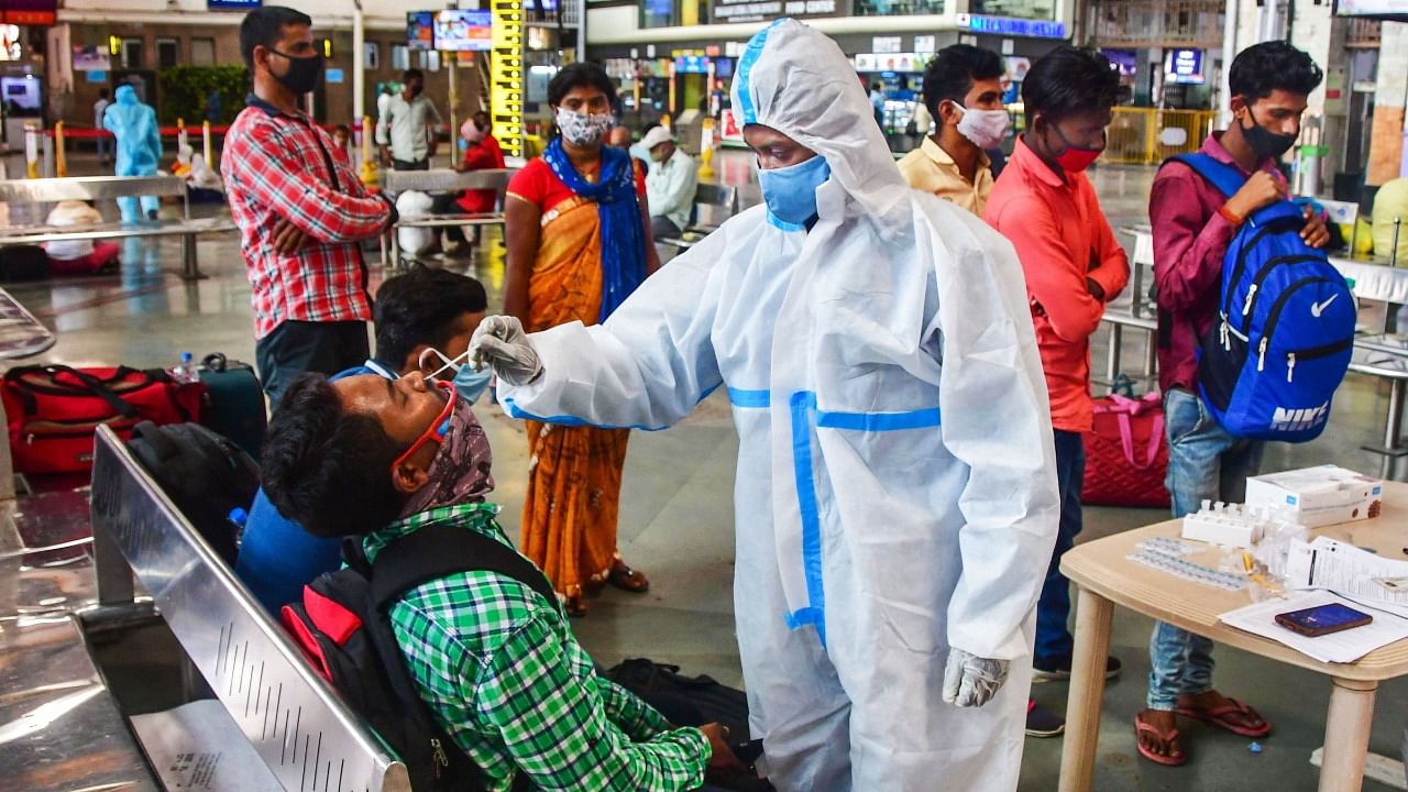 A health worker takes a swab sample of a passenger for coronavirus tests at the CSMT railway station, amid surge in Covid-19 cases, in Mumbai on March 17, 2021. Credit: PTI Photo
