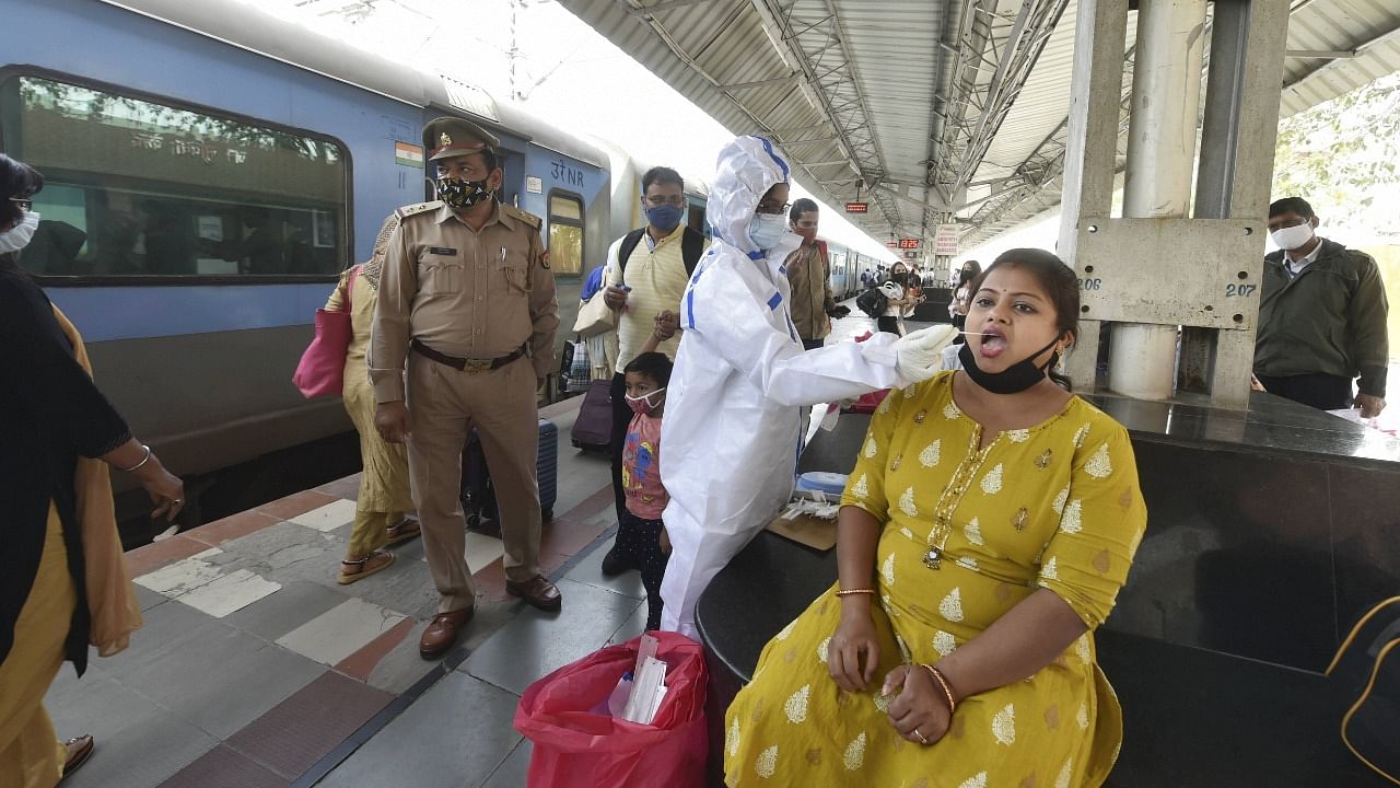 A medic collects swab sample of a passenger for Covid-19 test at Charbagh Railway Station in Lucknow. Credit: PTI Photo
