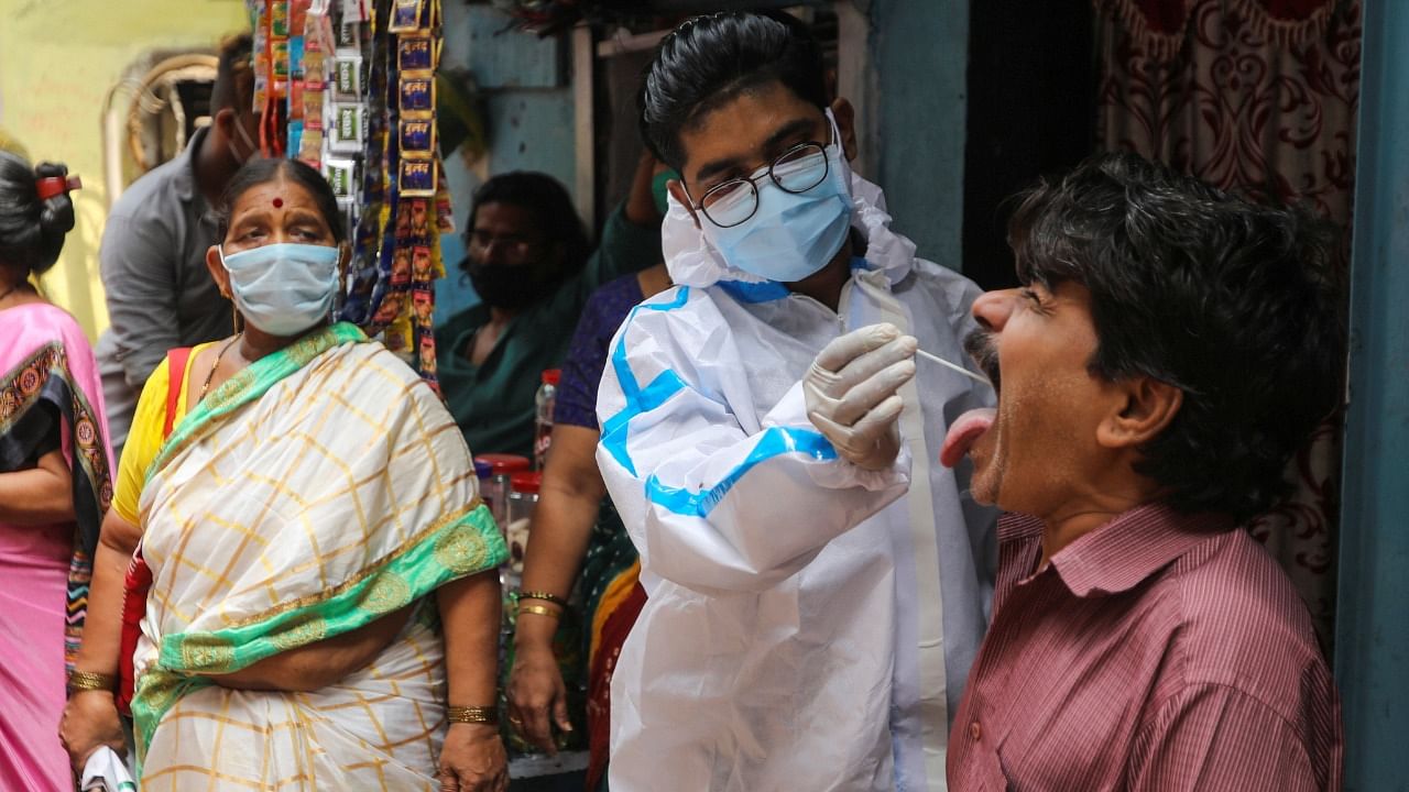 A health worker in personal protective equipment (PPE) collects a swab sample from a man during a testing campaign for the coronavirus disease, at a slum area in Mumbai, March 18, 2021. Credit: Reuters Photo