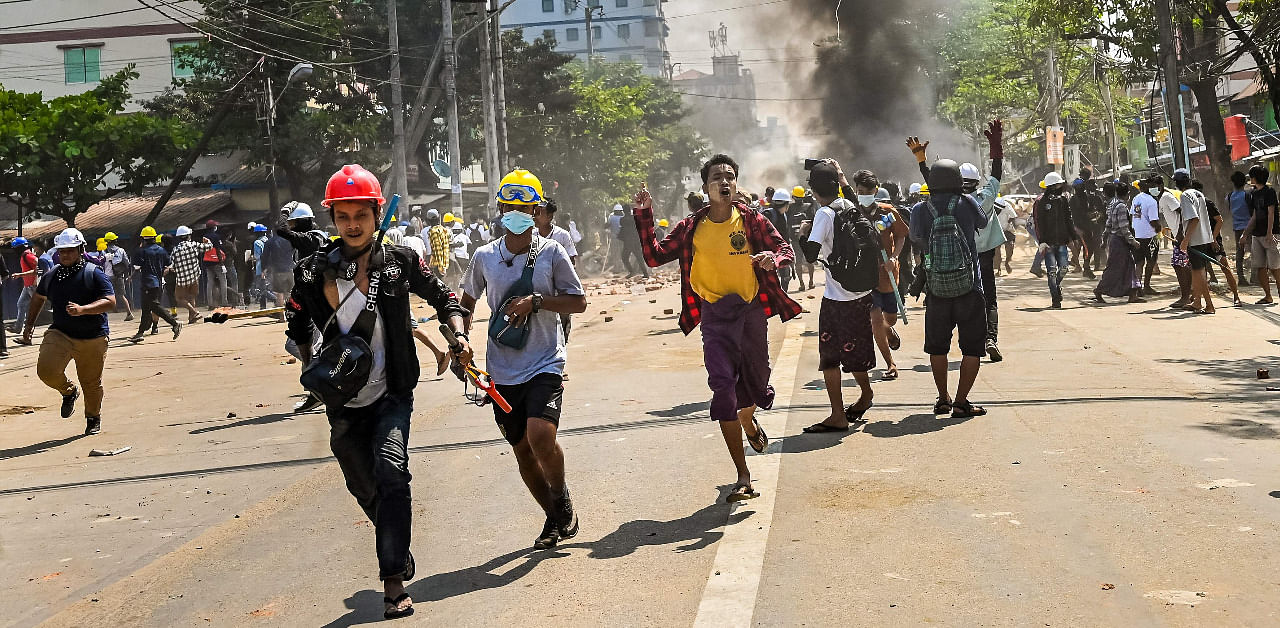 Protesters run as tear gas is fired during a crackdown by security forces on a demonstration against the military coup in Yangon's Thaketa township. Credit: AFP Photo