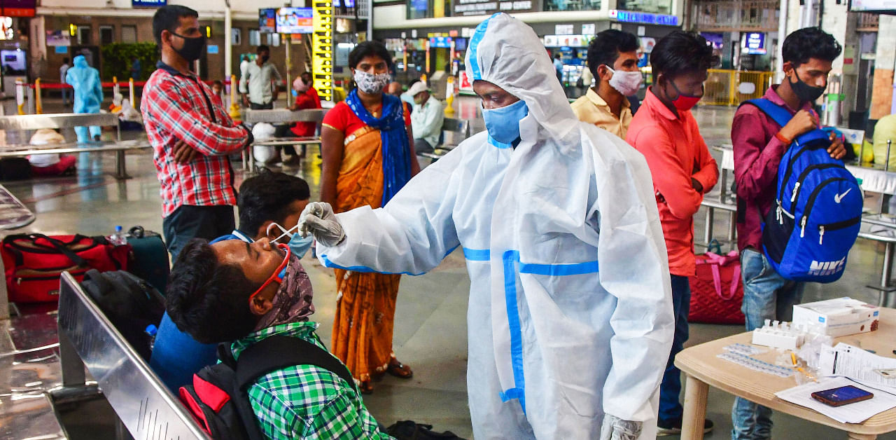 A health worker takes a swab sample of a passenger for coronavirus tests at the CSMT railway station, amid surge in Covid-19 cases, in Mumbai. Credit: PTI Photo