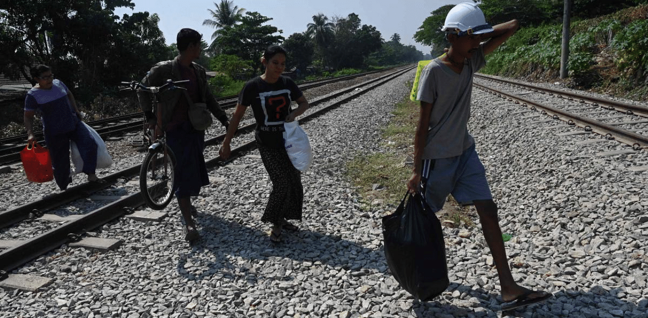 Railway staff carry their belonging as they flee by train tracks after security forces arrived at the Mahlwagone Railway Station to arrest workers involved in the Civil Disobedience Movement (CDM), in protest over the military coup, in Yangon. Credit: AFP Photo