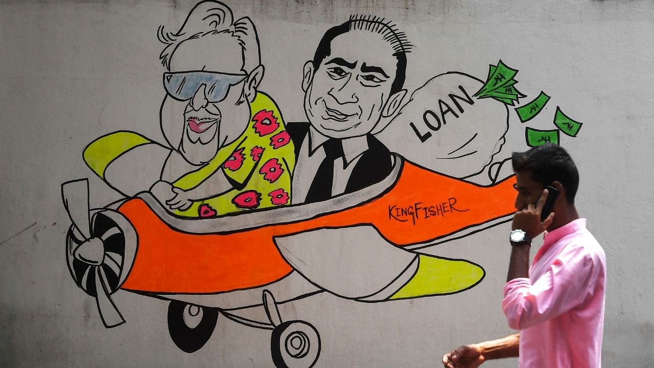 In this file photo taken on April 2, 2019, an Indian commuter walks past wall art graffiti displaying cartoons of Indian businessmen Vijay Mallya (L) and Nirav Modi (R), in Kolkata. Credit: AFP File Photo