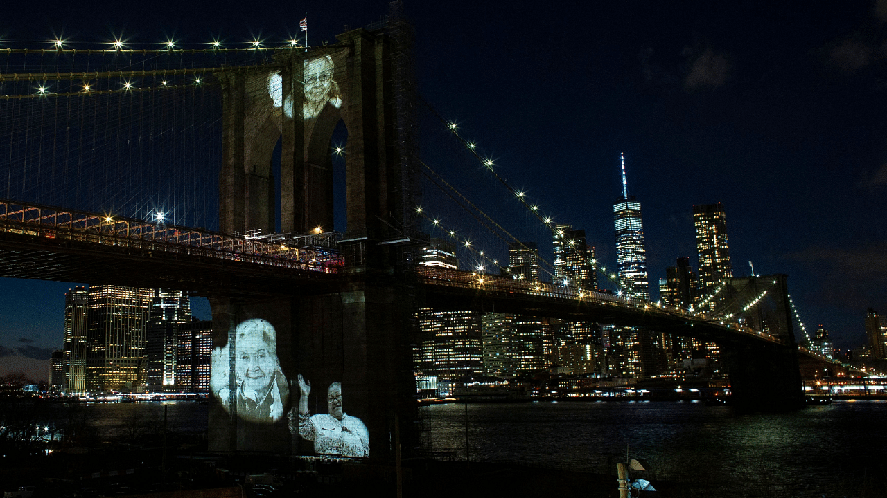 Images of Covid-19 Victims are projected over the Brooklyn bridge as the city commemorates a Covid-19 Day of Remembrance. Credit: AFP Photo