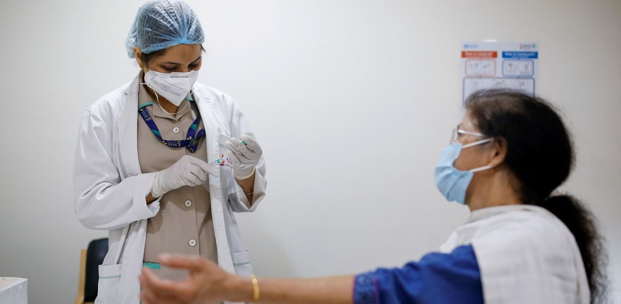 A woman watches as a healthcare worker fills a syringe with a dose of Covishield. Credit: Reuters Photo