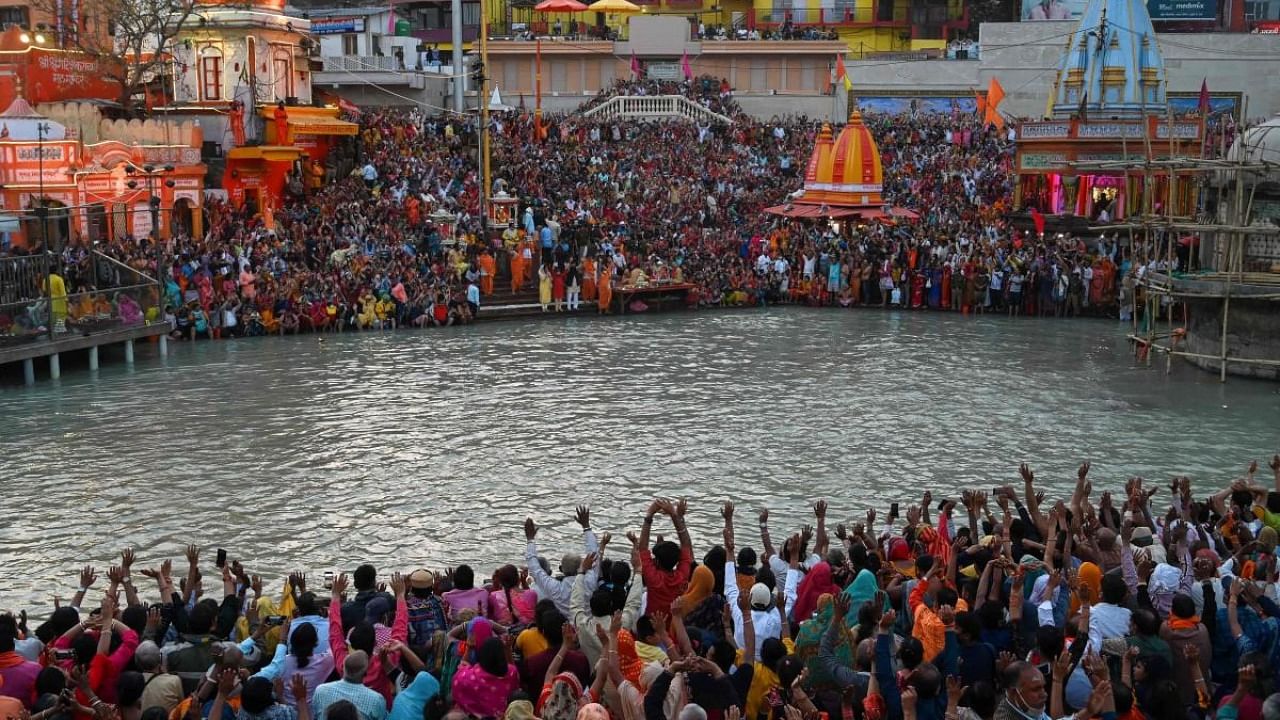 Hindu devotees attend evening prayers after taking a holy dip in the waters of the River Ganges on the Shahi Snan (grand bath) on the occasion of the Maha Shivratri festival during the Kumbh Mela. Credit: AFP file photo.