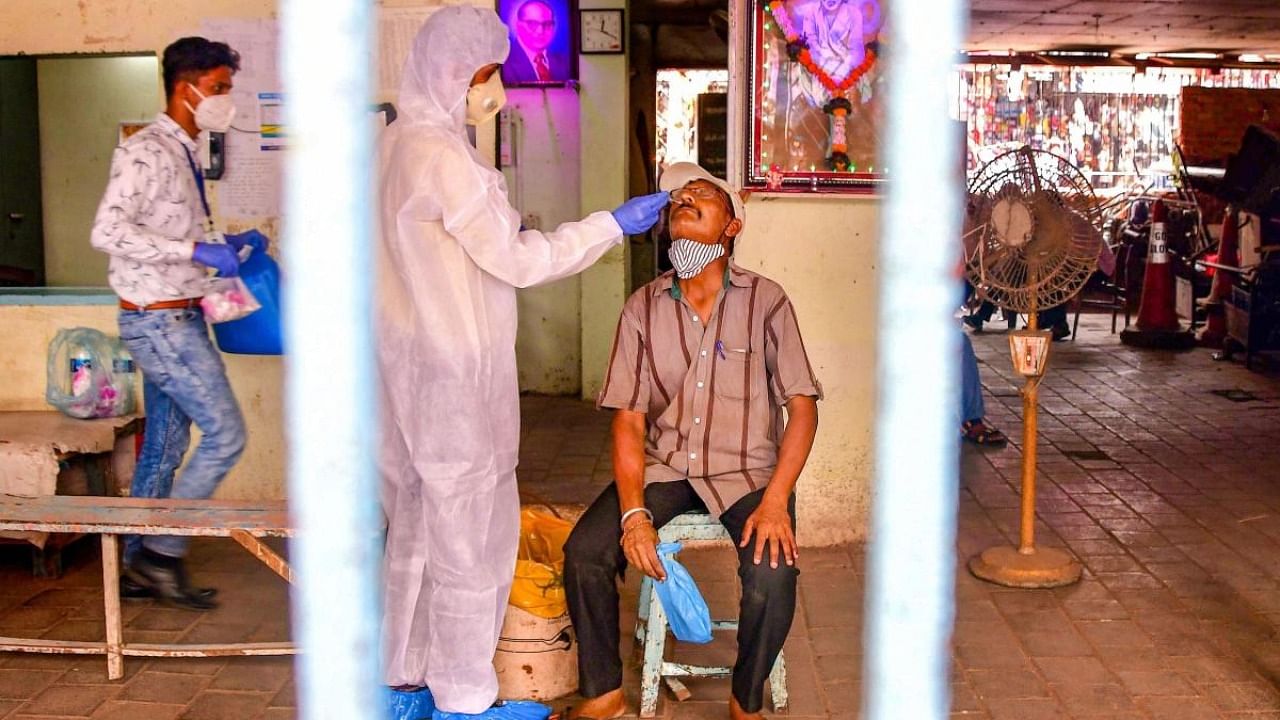 A heath worker, wearing PPE, conducts Covid-19 testing of a man at Dadar market, amid a surge in coronavirus cases across Maharashtra, in Mumbai. Credit: PTI.