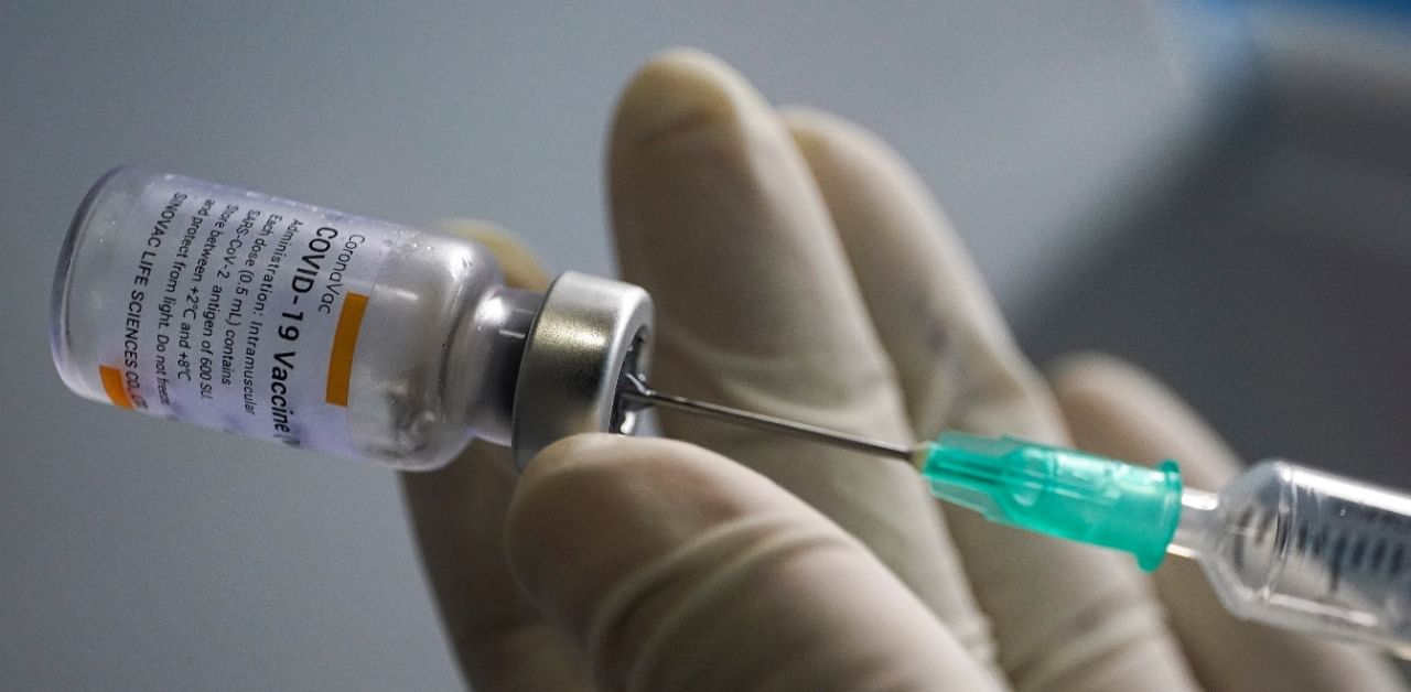 A health worker holds a syringe and a vial of the Sinovac vaccine. Credit: Reuters Photo