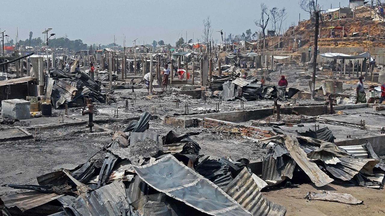 People are seen amidst the debris at a Rohingya refugee camp in Ukhia after a huge blaze forced around 50,000 people to flee. Credit: AFP Photo