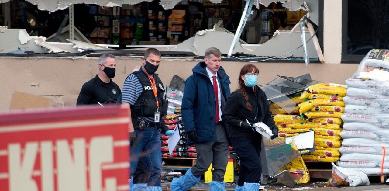 Crime scene investigators, with Boulder County District Attorney Michael Dougherty (2nd R), walk outside the entrance of the King Soopers grocery store in Boulder, Colorado after a mass shooting. Credit: AFP Photo