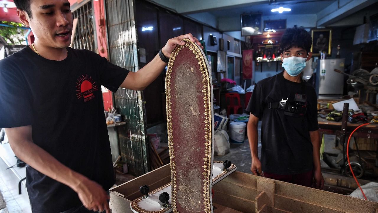 Coffin-maker Anusorn Yungyearn displaying a skateboard, made from wood used for coffins. Credit: AFP Photo