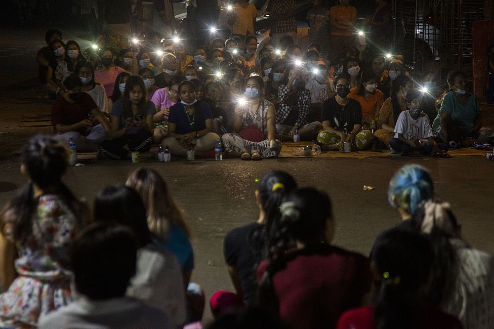 Residents flash the lights from their mobile phones during an anti-coup rally held despite an overnight curfew at the Myaynigone area of Sanchaung township in Yangon, Myanmar. Credit: AP Photo