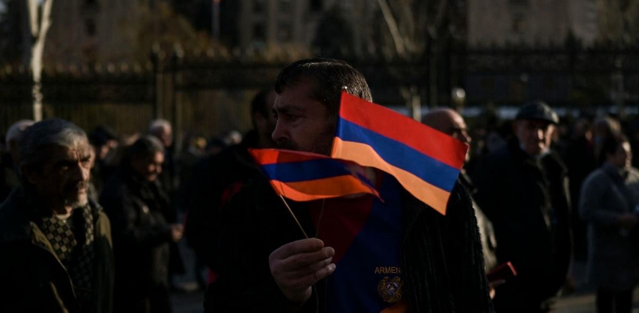 A protester holds national flags during a rally outside the National Assembly building to demand the resignation of the prime minister over his handling of last year's war with Azerbaijan, in Yerevan on March 3, 2021. Credit: AFP Photo