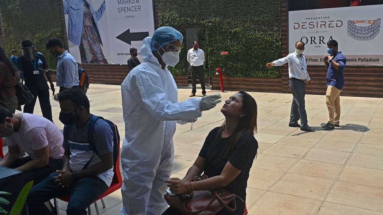 A health worker takes a nasal swab sample of a visitor at the Phoenix mall as mandated by the civic authorities to undergo Covid-19 coronavirus Rapid Antigen Test (RAT) in Mumbai. Credit: AFP Photo