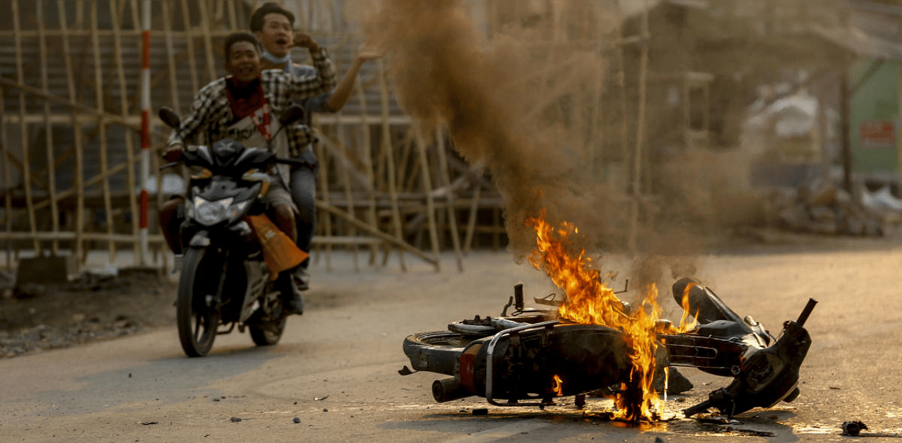 Two men on a motorbike alert people and anti coup protesters as armed security forces arrive to crack down on a demonstration in Mandalay, Myanmar. Credit: AP photo. 