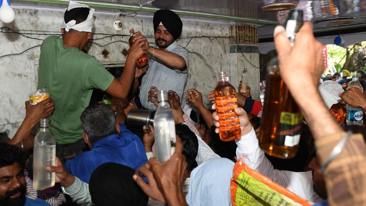 Devotees hold bottles of liquor at Baba Rode Shah shrine in Amritsar. Credit: AFP Photo