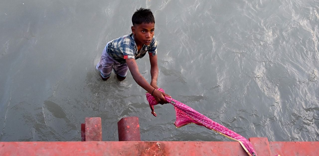 A boy waits to catch offerings thrown by Hindu devotees in Ganges. Credit: AFP Photo
