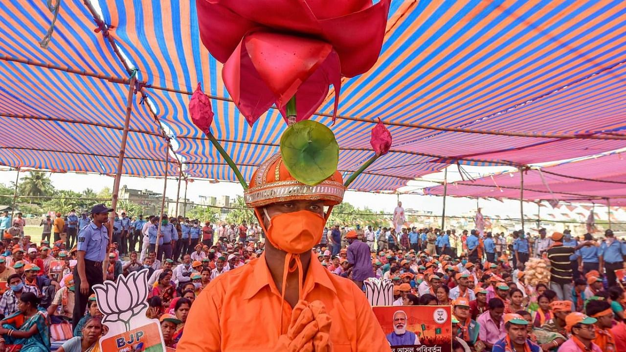 A BJP supporter, dressed in party colors and symbol, attends a rally by Union Home Minister Amit Shah, ahead of state assembly polls at Mecheda in East Midnapore district. Credit: PTI.