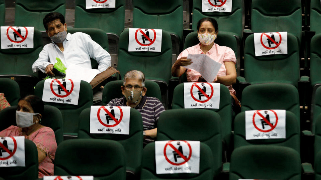 People sit under observation after receiving a dose of COVISHIELD, the coronavirus disease vaccine manufactured by Serum Institute of India, at an auditorium, which has been converted into a temporary vaccination centre in Ahmedabad. Credit: Reuters File Photo