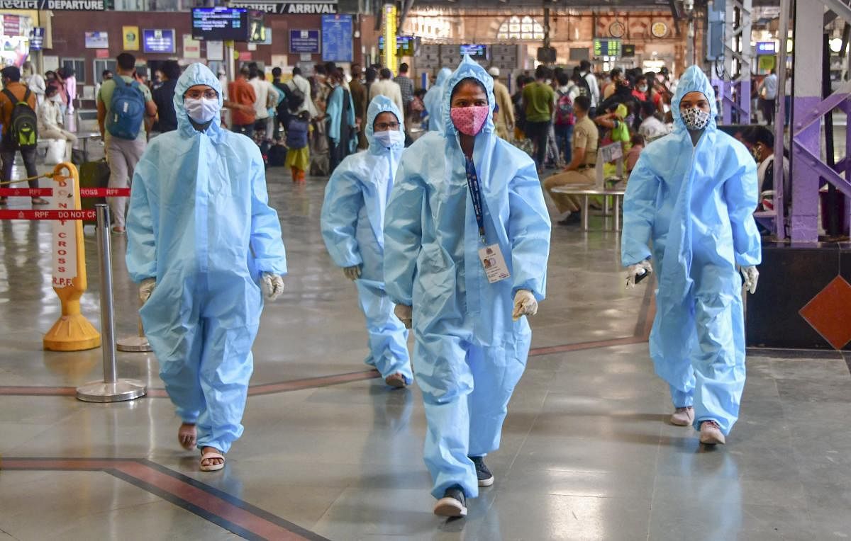 Health workers wearing PPE kits walk on a platform at CSMT station in Mumbai on Wednesday. PTI