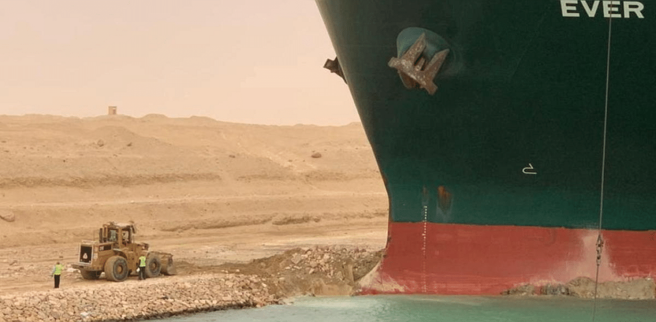 Workers are seen next to a container ship which was hit by strong wind and ran aground in Suez Canal, Egypt. Credit: Reuters photo. 