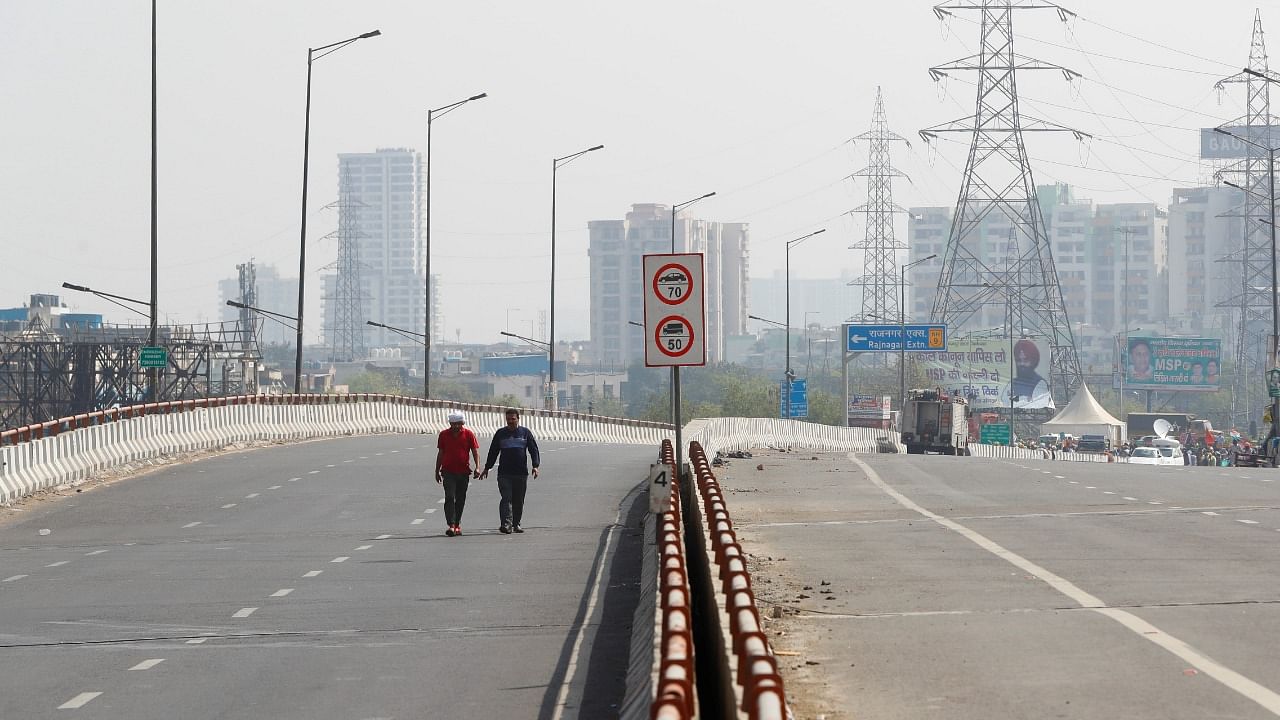 Farmers walk on a deserted road during a 12-hour strike, as part of protests against farm laws, on a highway at the Delhi-Uttar Pradesh border in Ghaziabad. Credit: Reuters Photo
