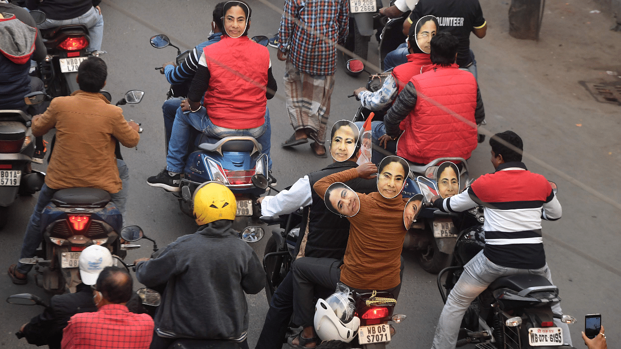  Trinamool Congress (TMC) party workers on their motorbikes wearing face cut-outs of West Bengal state Chief Minister Mamata Banerjee. Credit: AFP Photo