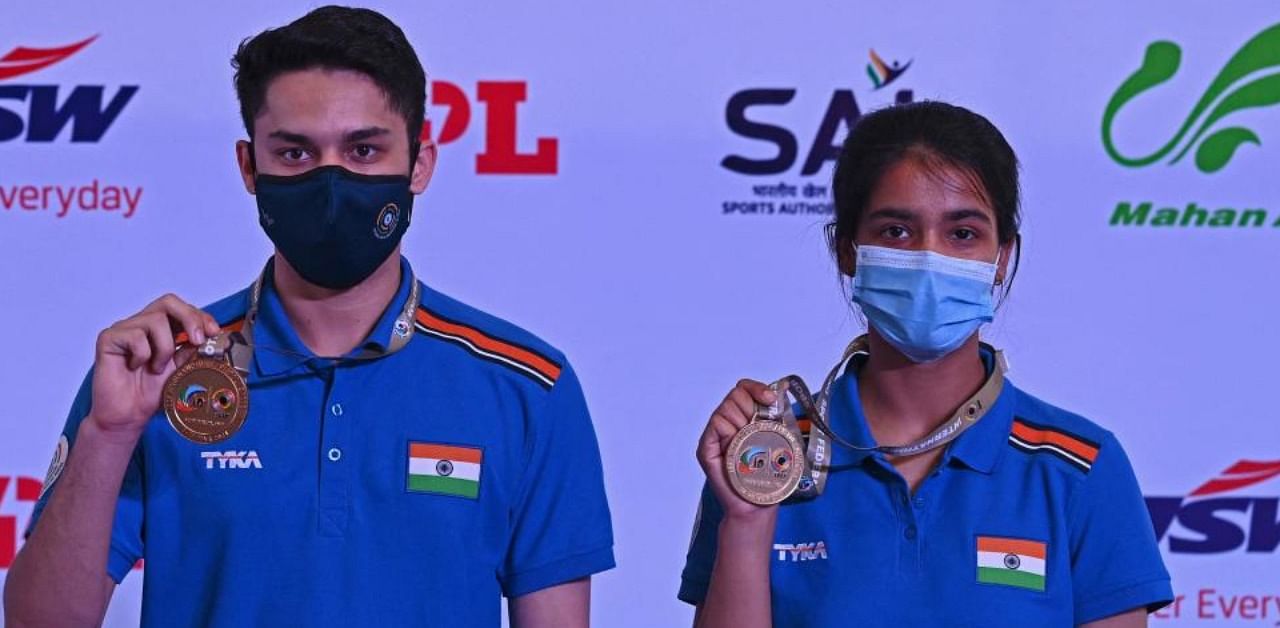 Vijayveer Sidhu (L) and Tejaswani (R) pose with their gold medials after winning the double mixed in 25M Rapid fire  pistol mixed teams  final of the ISSF World Cup 2021, at the Karni Singh shooting range in New Delhi on March 27, 2021. Credit: AFP Photo