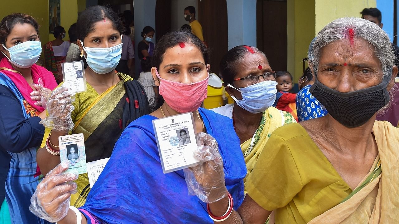 Women show their identity cards as they wait to cast votes at a polling station, during the first phase of Assembly polls, in Midnapore, Saturday, March 27, 2021. Credit: PTI Photo