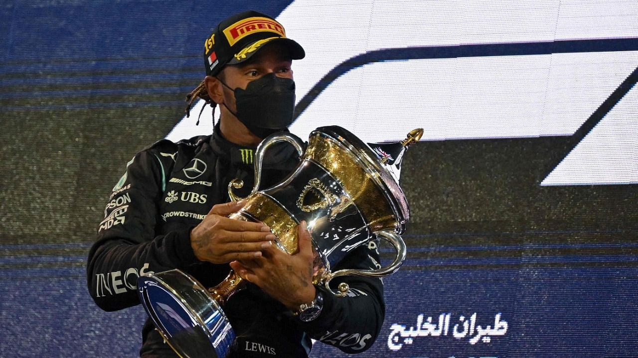 Mercedes' British driver Lewis Hamilton holds the winner's trophy on the podium after the Bahrain Formula One Grand Prix at the Bahrain International Circuit. Credit: AFP Photo