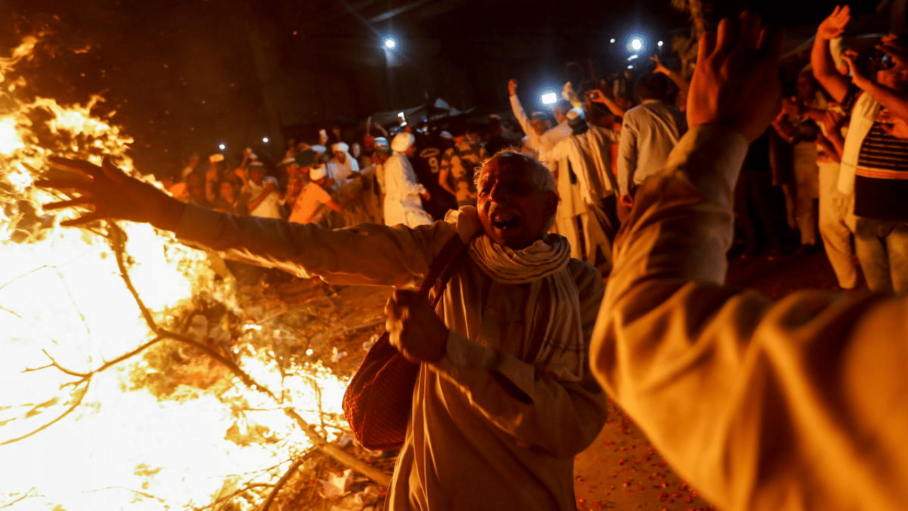 A farmer dances after burning farm law copies in a bonfire during a ritual known as "Holika Dahan" as part of the Holi celebrations, at the site of a protest against the new farm laws, at the Delhi-Uttar Pradesh border in Ghaziabad. Credit: Reuters Photo