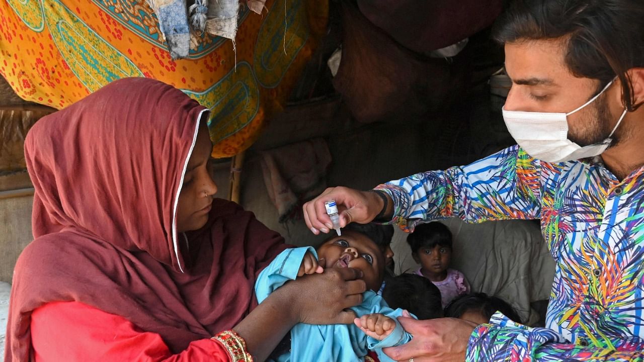 A health worker administers polio vaccine drops to a child during a polio vaccination door-to-door campaign at a slum area in Lahore. Credit: AFP Photo