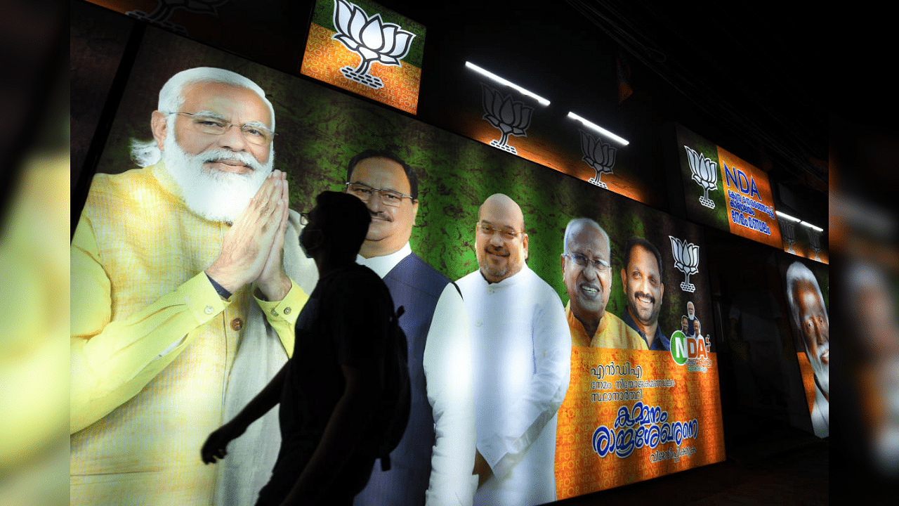  A youth walks past campaign posters of BJP national leaders near NDA Central Committee Office, ahead of Kerala assembly polls, in Thiruvananthapuram, Tuesday, March 23, 2021. Credit: PTI Photo