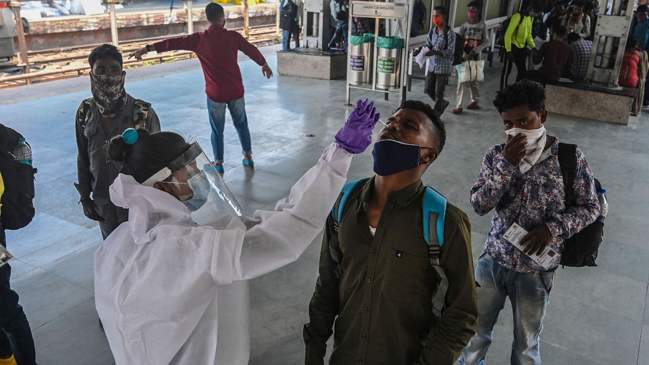 A health worker takes a swab sample for a Rapid Antigen Testing (RAT) from passengers arriving into the city at a railway terminus as made mandatory by the state government due to a rise in Covid-19 coronavirus cases, in Mumbai on March 29, 2021. Credit: AFP Photo