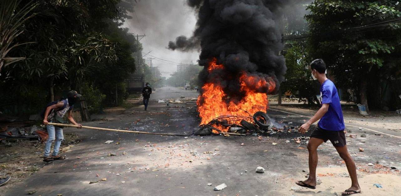 An anti-coup protester walks past burning tires, in Yangon. Credit: Reuters Photo