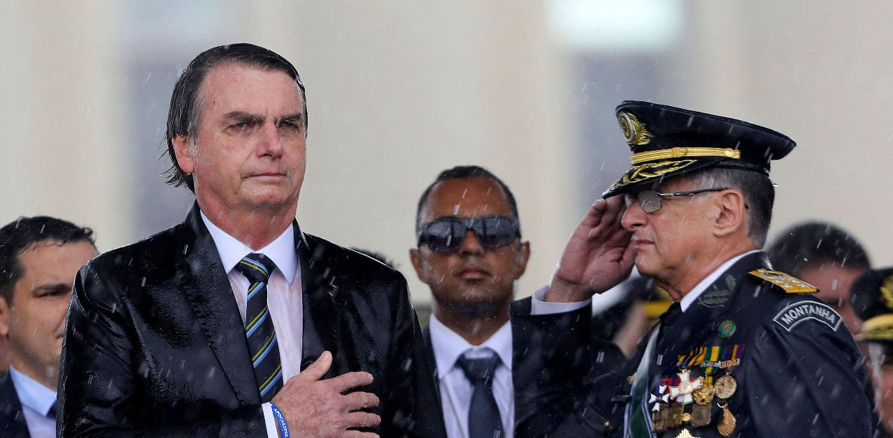 Brazilian President Jair Bolsonaro (L) and Army Commander Edson Pujol are drenched with rain as they attend a ceremony to mark Army Day. Credit: AFP Photo