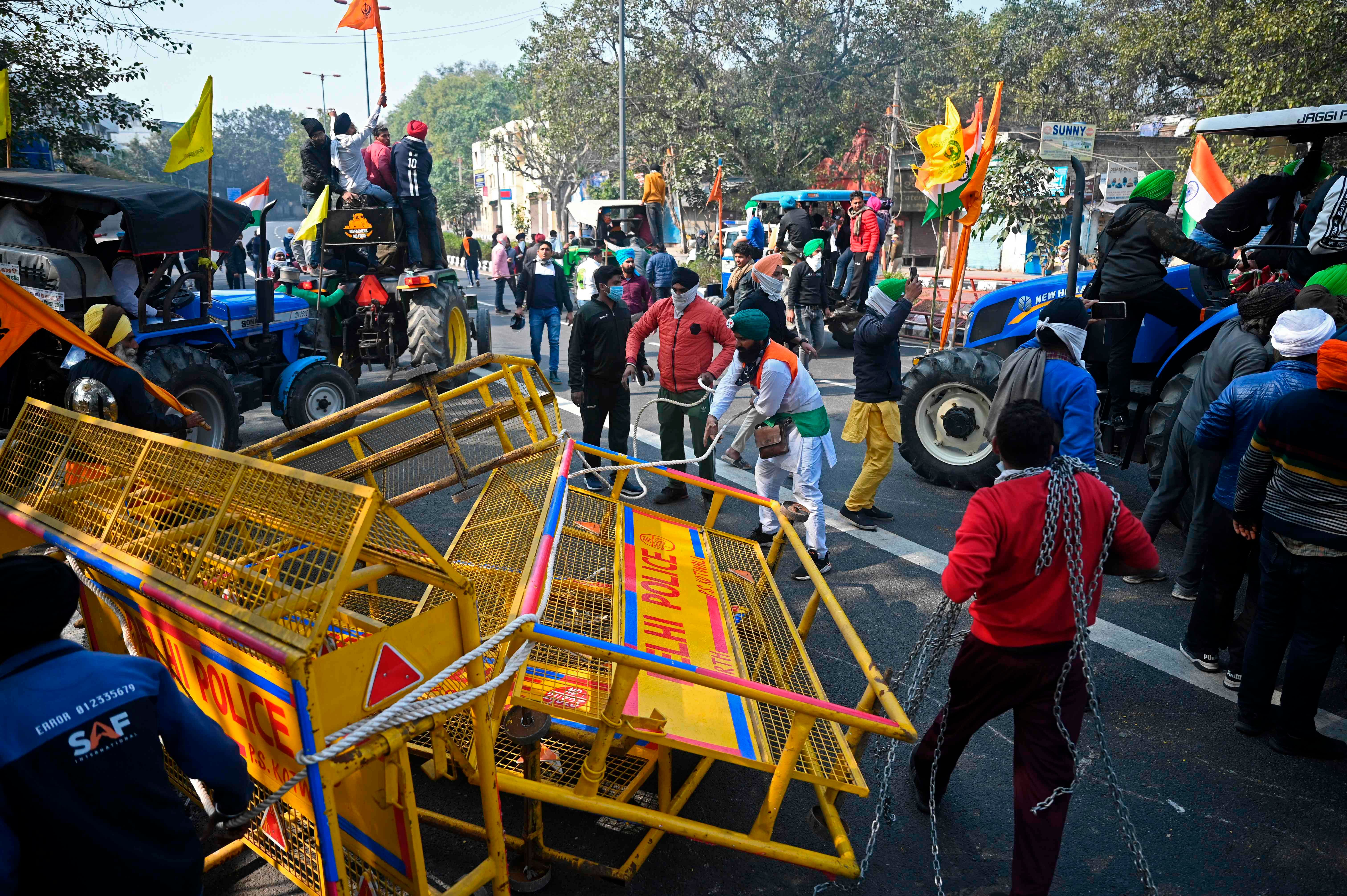 Farmers on tractors prepare to remove concrete barricades during teh tractor rally on republic Day in New Delhi. Credit: AFP