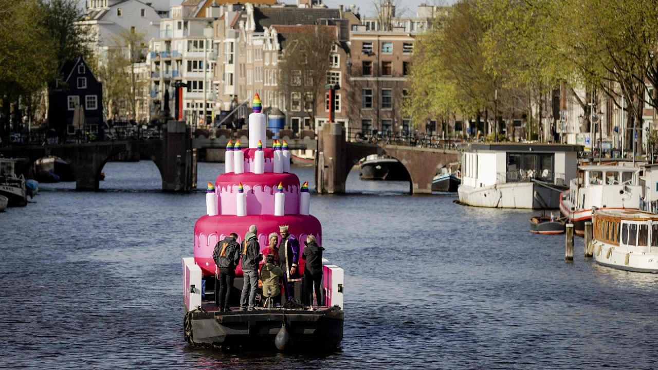 A bridal couple who got married four years ago, sails on a special anniversary boat across the canals exactly 20 years ago, when the first rainbow wedding was concluded in Amsterdam. Credit: AFP Photo