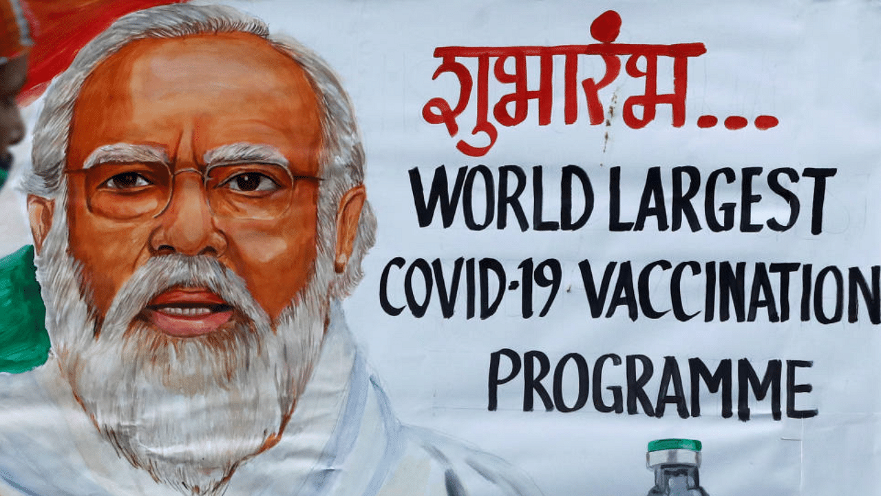  A woman walks past a painting of PM Narendra Modi a day before the inauguration of the COVID-19 vaccination drive on a street in Mumbai. Credit: Reuters Photo