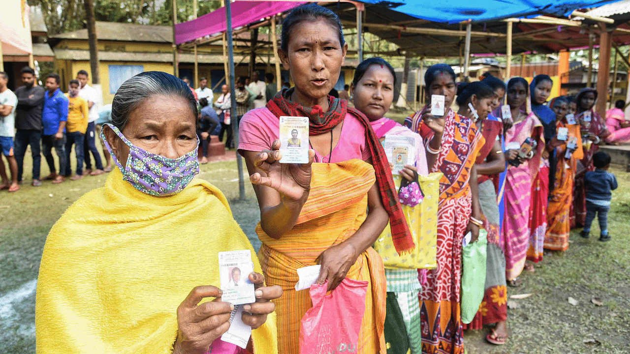 Tribal women wait to cast their votes during the second phase of Assam Assembly polls, in Morigaon. Credit: PTI Photo