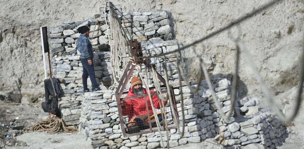 A villager crosses a river on a manually operated trolley, recently installed by the PWD following the glacier burst at Joshimath which triggered a massive flash flood on Feb. 7, in Chamoli district of Uttarakhand, Tuesday, Feb. 16, 2021. Credit: PTI Photo