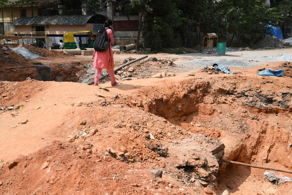 A woman walks as undergrounds pipes are placed on Palace Road, Bengaluru on Wednesday, March 31, 2021. DH Photo/Pushkar V