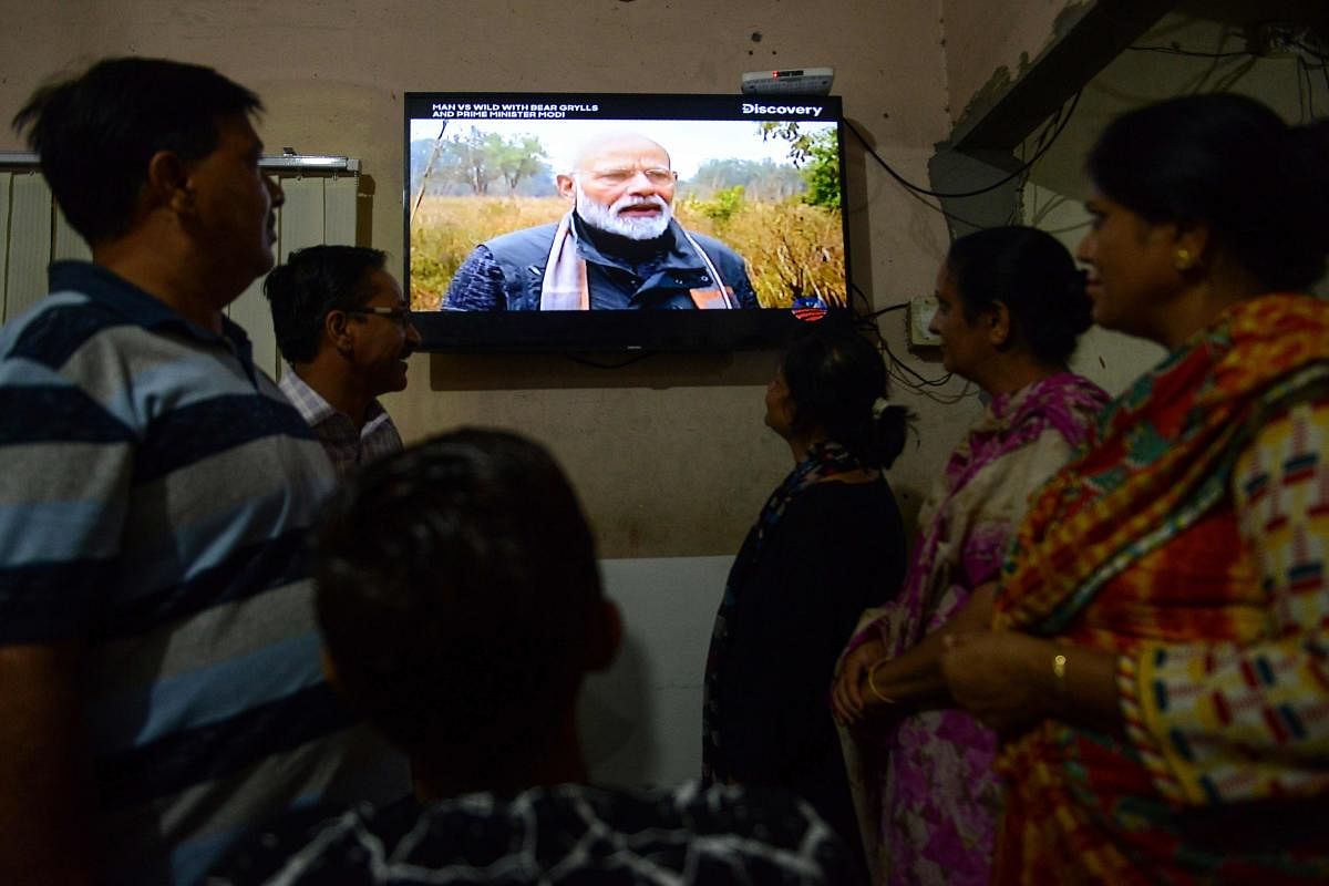 People watch on television the 'Man VS Wild' hosted by survival expert Bear Grylls, going on a mission with Indian Prime Minister Narendra Modi (C), in Amritsar on August 12, 2019. (AFP)