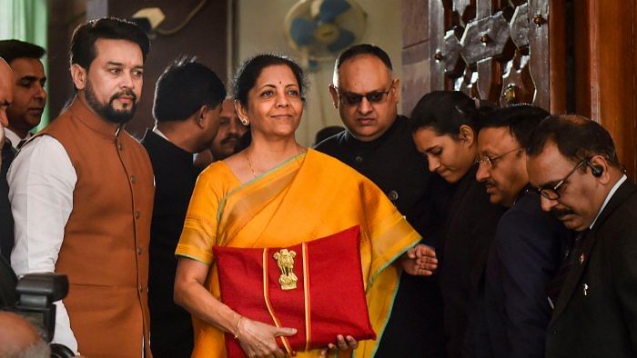 Union Finance Minister Nirmala Sitharaman, flanked by her deputy Anurag Thakur (to her right) and a team of officials, shows a folder containing the Union Budget documents as she poses for lensmen on her arrival at Parliament in New Delhi. Credit: PTI File Photo