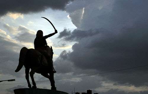 Statue of Kittur Chennamma is silhouetted against the dark clouds hovering over city skies. Photo by Anantha Subramanyam K
